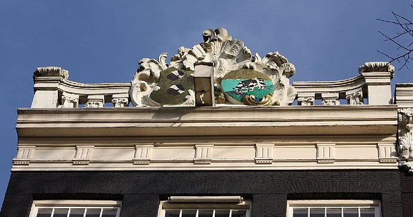 Keizersgracht 135. Rechte lijst met attiek in de vorm van een balustrade en twee wapenschilden